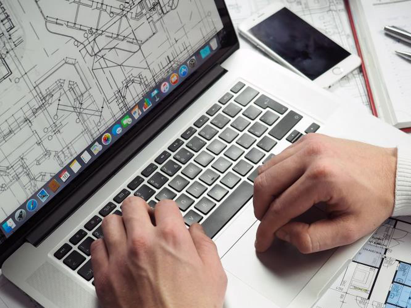 Werkvoorbereider met plattegronden en een tekening op zijn laptop